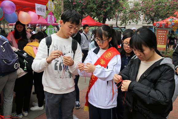 志愿者耐心地教同学们编织中国结